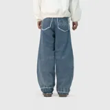 Pantalón de jean estilo baggy, de corte extremadamente holgado y tiro medio. Presenta bolsillos traseros con bordes deshilachados y un diseño de llamas bordado en uno de ellos. El ruedo cuenta con un acabado reforzado y ancho.