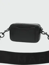 Cartera tipo crossbody Marc Jacobs modelo The Snapshot, color negro con acabado monocromático. Presenta el logo metálico frontal, doble compartimento con cierre y correa ajustable de tela.