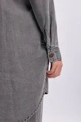 Camisa de jean de corte oversize y largo tipo túnica en color gris desgastado, con mangas largas, cuello camisero y cierre frontal de botones.