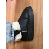 Pantuflas botitas color tostado con diseño acolchado y plataforma, forradas con corderito sintético blanco en el interior y el cuello. Cuentan con una pequeña etiqueta decorativa en el lateral.