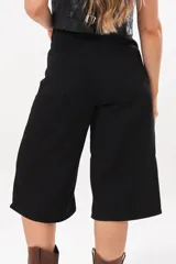 Bermuda de tiro medio y silueta amplia en color negro, con bolsillos delanteros y traseros, y cierre frontal con cremallera y botón.