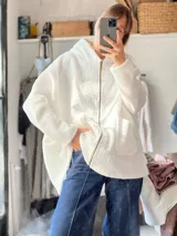 Campera con capucha confeccionada en tejido tipo corderito blanco, con diseño de collage abstracto en la espalda en tonos rosado y marrón. Presenta un corte holgado y una etiqueta de cuero sintético en la parte inferior.