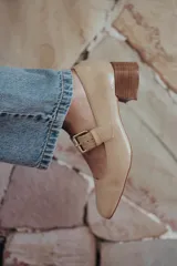 Zapato de charol negro con hebilla metálica ajustable y taco cuadrado.