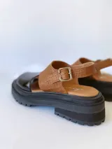 Sandalias de cuero color negro y camel, con plataforma track y hebilla ajustable.
