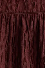 Pollera evasé midi de punto texturizado en color bordó, con elástico en la cintura y costura fruncida con ribete de cinta bajo la cadera.