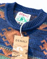 Buzo tejido de punto con diseño geométrico de estilo étnico. Presenta cuello redondo, puños y ruedo acanalados. Confeccionado en una mezcla de lana y fibras sintéticas, con etiqueta de marca en el pecho y en el ruedo.