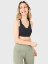 Top deportivo de soporte alto en color negro, con tirantes ajustables y cierre de ganchos en la espalda. Cuenta con almohadillas removibles y diseño con apertura en la espalda para mayor ventilación.