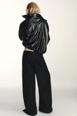 Jeans de corte baggy y tiro medio en color negro. Presenta diseño de cinco bolsillos y detalle de cremalleras verticales en el frente de las piernas con efecto torcido.