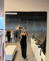 Vestido largo negro de tirantes finos, con escote festoneado y corte al cuerpo con abertura lateral en la falda.