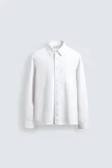 Camisa de corte regular fit confeccionada en denim ligero con mezcla de lyocell, algodón y lino. Presenta cuello solapa, cierre frontal de botones, manga larga con puños abotonados y un bolsillo en el pecho.
