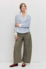 Camisa de rayas celestes y marrones, de corte holgado y manga larga, con cuello en V y detalles blancos en el cuello y los puños.