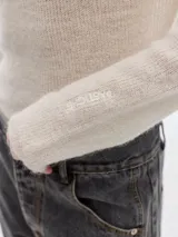 Polera azul de tejido suave con cuello alto y manga larga. Tiene un pequeño bordado en el frente y otro en la manga.