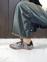 Championes tipo derby con capellada de cuero con textura de pelo y estampado animal print de cebra. Cuenta con suela de goma y cordones negros.