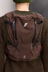 Chaleco deportivo técnico de malla transpirable en color negro, diseñado para running y actividades al aire libre. Cuenta con múltiples compartimentos, bolsillos con cremalleras termoselladas, cierres frontales de hebilla de liberación rápida y ajuste lumbar mediante cordón elástico.