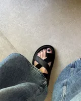 Sandalias negras de cuero vacuno con tiras cruzadas y hebilla lateral.