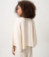 Blusa tipo bata color off-white de viscosa y poliamida, con cuello redondo, mangas cortas amplias, fruncido bajo el busto y bordado delantero contrastante.