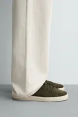 Zapatilla de cordones color verde militar, fabricada en piel con acabado serraje y suela plana color crema.