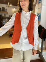 Chaleco reversible de lino, color naranja en el exterior y rayas finas en el interior, con cuello en V y cierre frontal de botones.