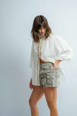 Short de jean gris claro con tiro medio, bolsillos delanteros y traseros, y cierre con botón y cremallera.