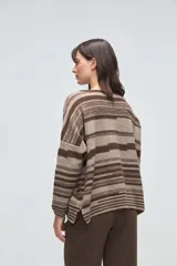 Buzo de tejido de punto con diseño de rayas horizontales en tonos beige y blanco, cuello redondo, hombros caídos y mangas largas.