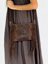 Cartera tipo bandolera color beige con textura símil cocodrilo y flecos.