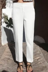 Pantalón de tiro medio con corte tobillero, bolsillos delanteros y falsos bolsillos de vivo en la parte trasera. Presenta cintura elástica en la espalda, cierre frontal con cremallera, botón interior y gancho, y aberturas laterales en el bajo.