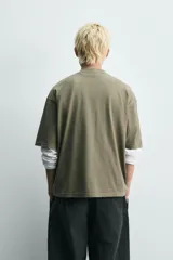 Camiseta de algodón con corte relajado, cuello redondo y manga corta. Presenta un estampado gráfico frontal en color negro con tipografía estilo deportivo y efecto desgastado.