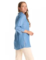 Blusa de lyocell color azul claro, con cuello camisero, escote en V y cierre frontal parcial con botones. Presenta mangas tres cuartos amplias y un corte holgado con aberturas laterales en el ruedo.