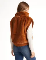 Chaleco de piel sintética en color beige, con cuello alto, cierre frontal metálico y terminaciones en tejido rib en el ruedo y sisas.