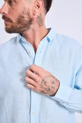 Camisa de corte regular con diseño de rayas verticales finas en tonos claros, cuello clásico y mangas largas con puños abotonados.