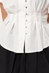 Blusa beige melange con escote en V, manga corta caída, botones metálicos frontales y pinzas que marcan la cintura.