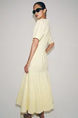 Vestido largo de Zara Woman Collection color amarillo claro, confeccionado en mezcla de algodón. Cuenta con escote en V, manga corta, corte en la cintura y falda evasé con pliegues marcados.