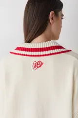 Cardigan de punto color chocolate con diseño de bloques de color y detalles a rayas en cuello, puños y ruedo. Presenta cierre frontal con botones, cuello tipo polo y dos bolsillos delanteros.