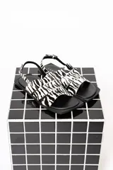 Sandalias chatas con tiras de cuero con estampado de cebra y base cuadrada.