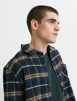 Sobrecamisa de manga larga con diseño a cuadros, cuello camisero y bolsillo frontal. Confeccionada en tejido de poliéster y algodón, sin forro.