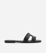 Sandalia plana marca Satinato de color negro, con diseño de tiras en forma de H en el empeine y puntera cuadrada.