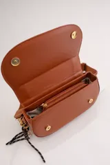Cartera bandolera de tamaño compacto en color camel, con diseño estructurado y solapa frontal. Incluye doble asa: una corta fija de cuero sintético y una correa larga estilo sport regulable. Cuenta con cierre de cremallera y broche imantado, además de un detalle de llavero colgante.