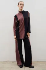 Pantalón de corte recto y tiro alto, confeccionado en algodón con diseño bicolor que combina paneles laterales en negro y panel central en beige, unidos por costuras visibles a contratono.