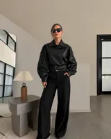 Campera de cuero sintético negro con textura de piel de serpiente, cuello mao y solapas, mangas abullonadas y cinto incorporado con hebilla metálica.