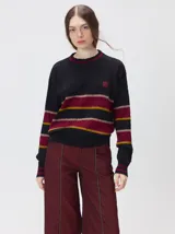 Sweater de punto cable con cuello redondo acanalado, mangas largas y puños ajustados. Presenta un diseño de rayas horizontales en tonos negro, bordó y mostaza, con logo bordado en el pecho.