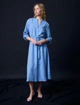 Vestido maxi color beige, con cuello mao y escote en V. Presenta mangas largas con presilla y botón para regular el largo, y un lazo ajustable en la cintura que marca la silueta.