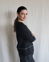 Remera blanca de manga larga con diseño de cuello en V y detalle de tablas frontales. Presenta mangas con sutil frunce en los hombros y puños rectos.