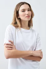 Remera blanca de algodón con mangas cortas de broderie, cuello redondo y corte recto.