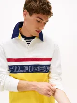 Chomba de rugby Tommy Hilfiger Sailing, unisex, de corte amplio y hombros caídos. Diseño color block blanco, amarillo y azul, con logo de la marca bordado en el pecho.