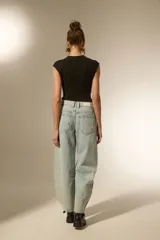 Pantalon de jean estilo baggy, color celeste lavado, con detalle de tachas metálicas en los bolsillos delanteros y a lo largo de las costuras laterales. Presenta un corte ancho y tiro bajo.