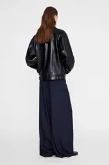 Chaqueta de cuero negro, estilo oversize con costuras a tono, botones plateados, bolsillos con solapa en el pecho y bolsillos laterales.