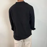 Camisa blanca de manga larga con cuello mao y abertura frontal con botones de madera. Tejido ligero con textura de lino.