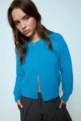 Cardigan corto de punto color rojo, con cierre frontal y cuello redondo. Presenta una textura acanalada y mangas largas.