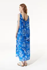 Vestido largo azul con estampado de estrellas de mar y flores. Tiene breteles finos regulables, cuello redondo y espalda descubierta.