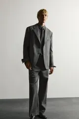 Pantalón de traje gris de corte relaxed fit, confeccionado en pura lana, con bolsillos laterales, bolsillos traseros de doble vivo y raya marcada en las piernas.
